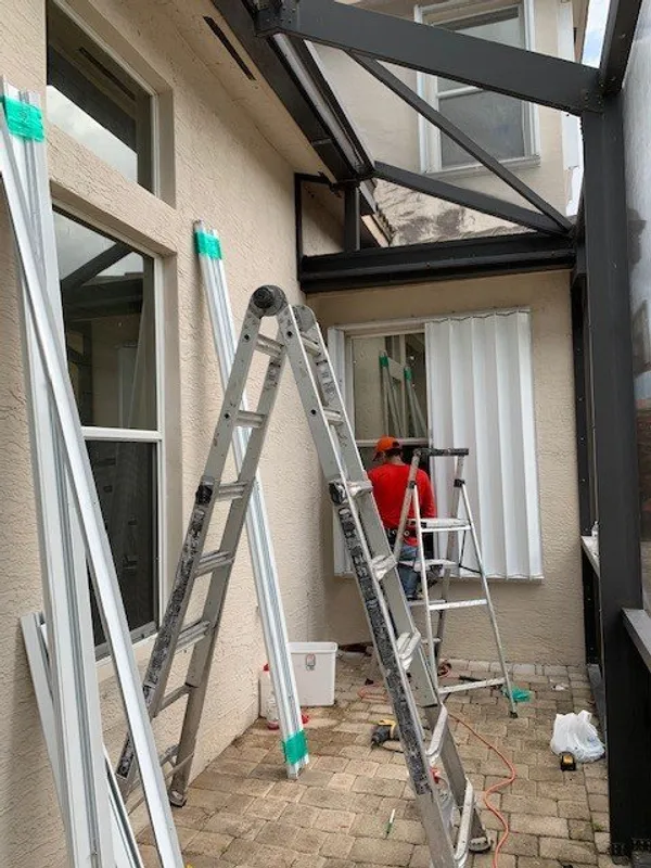 guy on ladder installing accordion shutters in boca